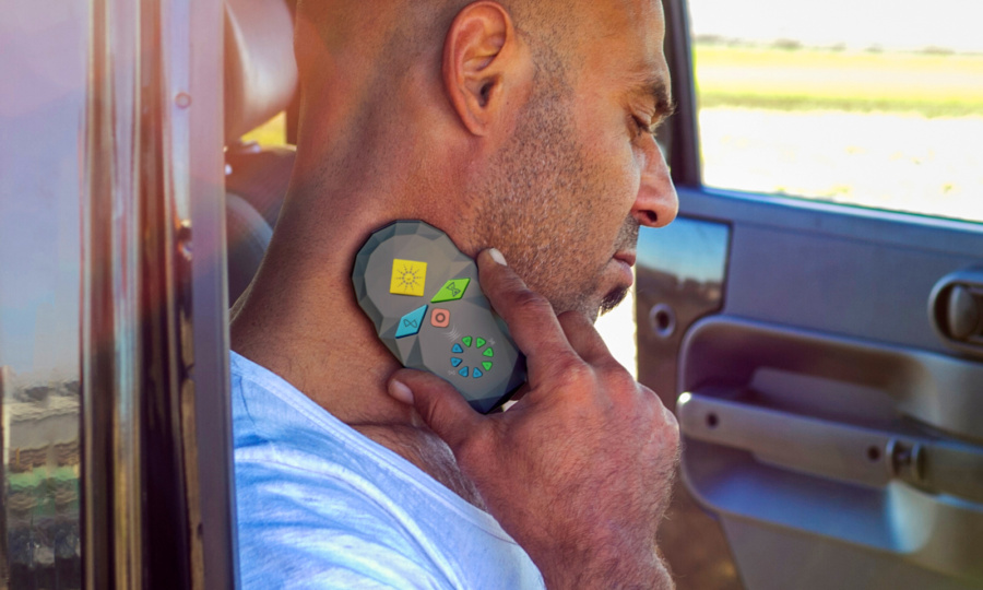 Man holding a coMra Palm device to his neck in a car